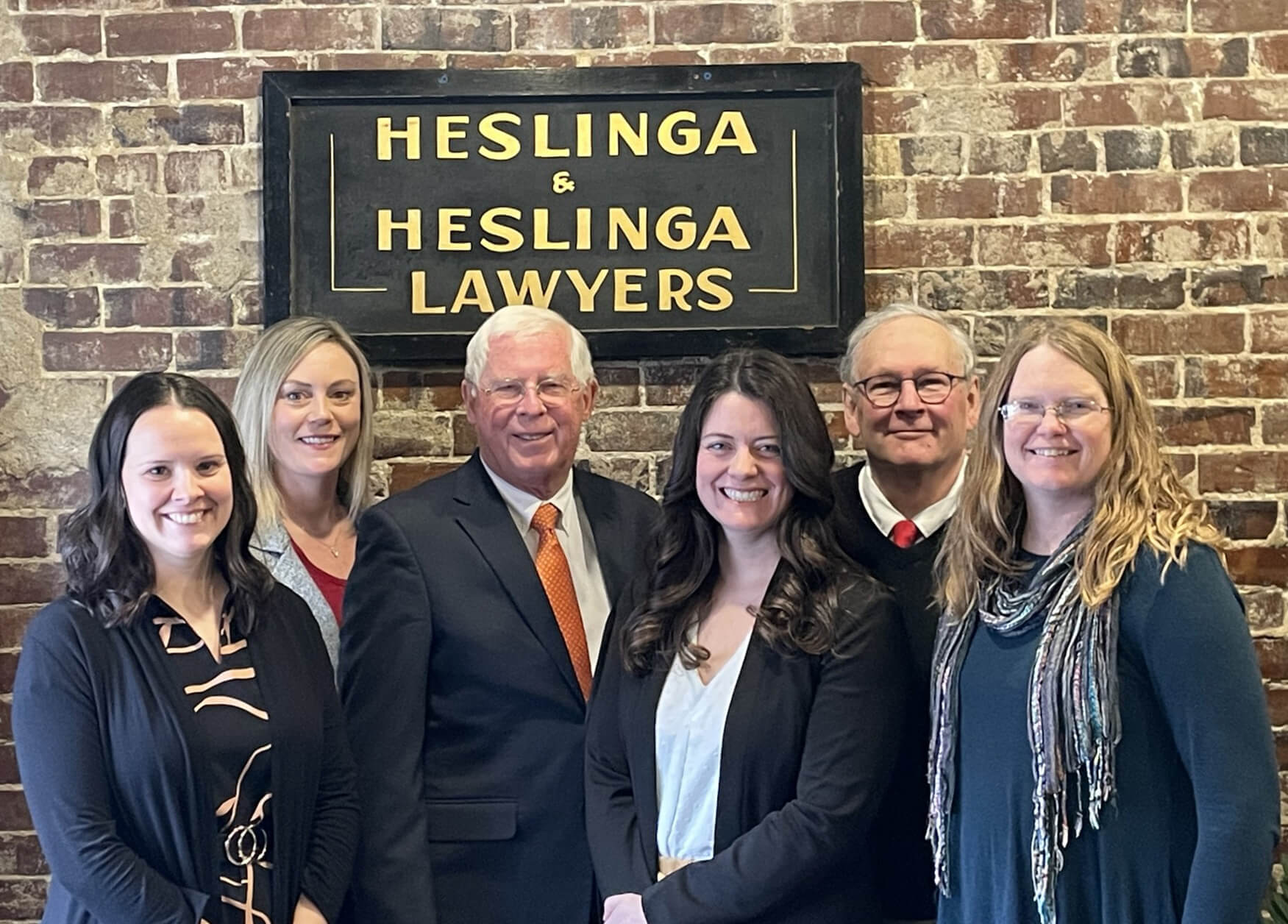 Hesling Law Firm staff members and attorneys standing in front of their office sign.